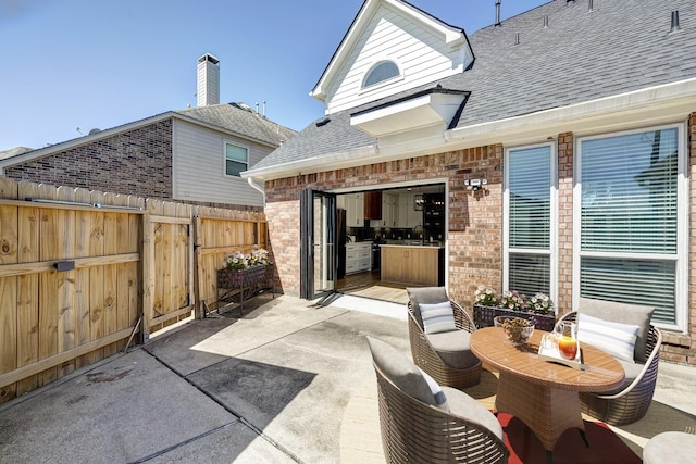 view of patio / terrace with a sink, fence, and concrete driveway