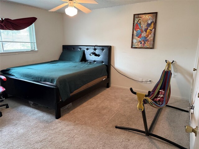 carpeted bedroom with ceiling fan and baseboards