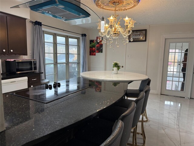 kitchen featuring dishwasher, stainless steel microwave, marble finish floor, black electric stovetop, and a textured ceiling