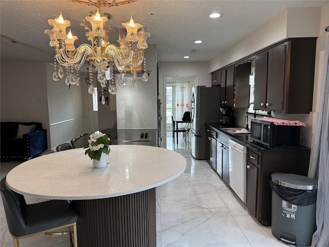 kitchen featuring black microwave, a textured ceiling, white dishwasher, freestanding refrigerator, and an inviting chandelier