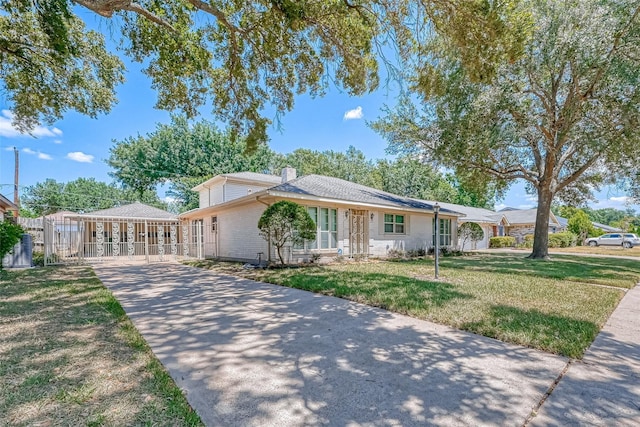 ranch-style house with driveway, a chimney, fence, a front lawn, and brick siding