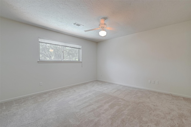 carpeted empty room with a ceiling fan, visible vents, a textured ceiling, and baseboards