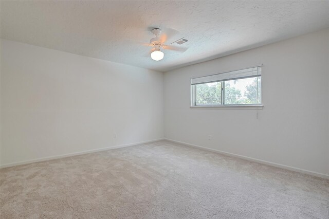 empty room featuring a textured ceiling, ceiling fan, visible vents, and light colored carpet