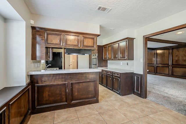 kitchen featuring visible vents, decorative backsplash, freestanding refrigerator, light carpet, and oven