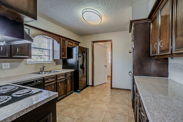 kitchen with light tile patterned floors, a sink, dark brown cabinets, backsplash, and black appliances