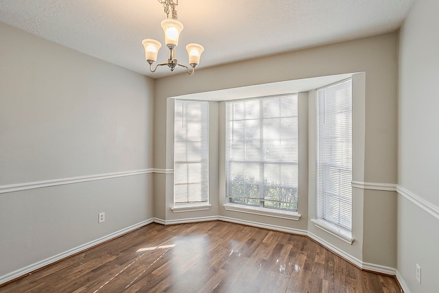 unfurnished dining area with a chandelier, wood finished floors, and baseboards