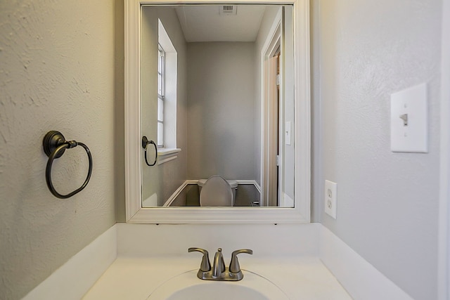 bathroom with visible vents, a sink, and a textured wall