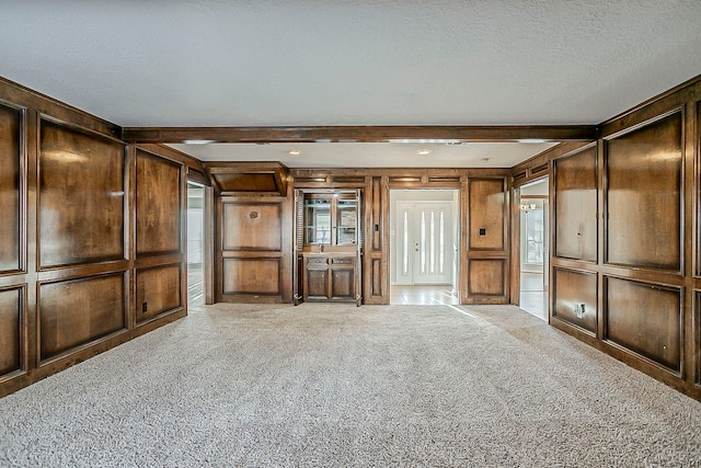 unfurnished living room featuring beam ceiling, carpet flooring, and a textured ceiling