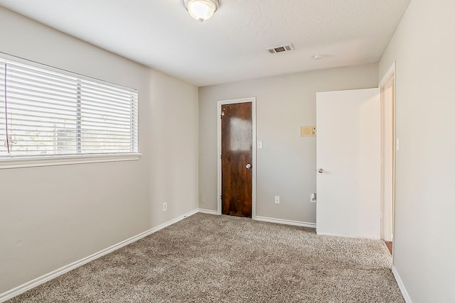 unfurnished bedroom featuring a textured ceiling, carpet flooring, visible vents, and baseboards