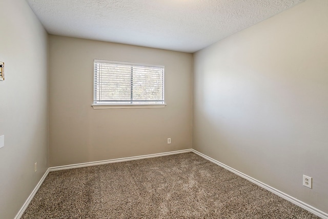 carpeted spare room featuring a textured ceiling and baseboards