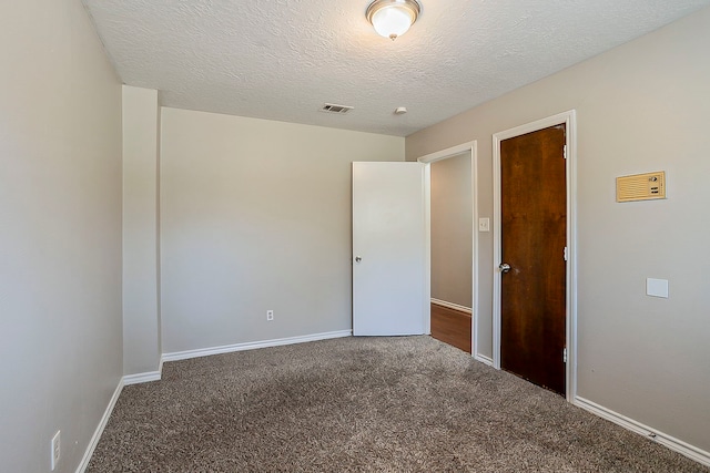 unfurnished bedroom with carpet, visible vents, baseboards, and a textured ceiling