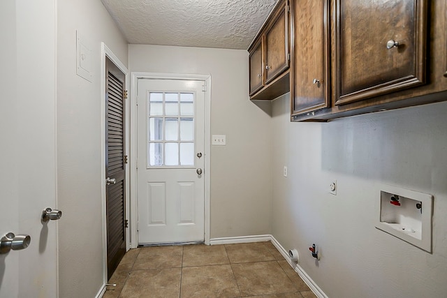 washroom with a textured ceiling, gas dryer hookup, light tile patterned flooring, washer hookup, and cabinet space