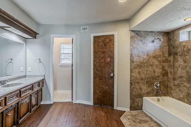 bathroom with wood finished floors, vanity, visible vents, baseboards, and shower / bathing tub combination