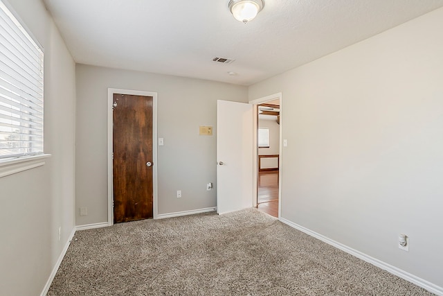 unfurnished bedroom featuring baseboards, visible vents, and carpet flooring