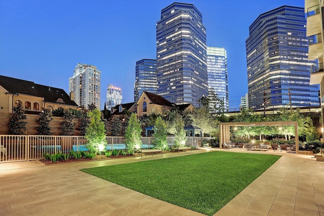 view of home's community with a patio area, fence, a city view, and a yard