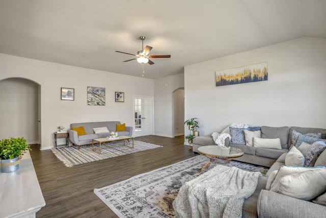 living room with dark wood-type flooring, baseboards, ceiling fan, vaulted ceiling, and arched walkways