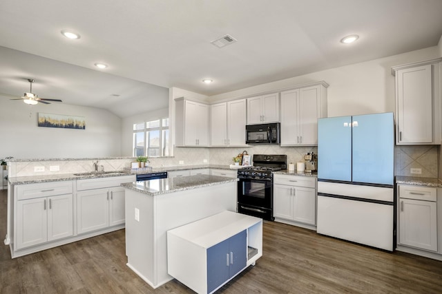 kitchen with a sink, visible vents, black appliances, and dark wood-style floors