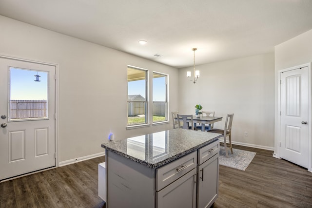 kitchen with baseboards, light stone countertops, hanging light fixtures, gray cabinets, and dark wood-style floors