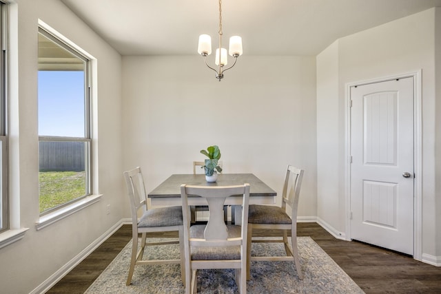 dining room with a chandelier, dark wood-type flooring, and baseboards