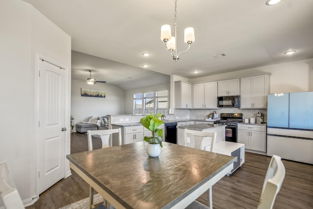 dining space with visible vents, vaulted ceiling, recessed lighting, ceiling fan with notable chandelier, and dark wood-style floors