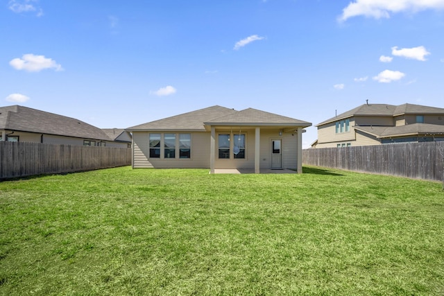 rear view of property featuring a patio, a lawn, and a fenced backyard