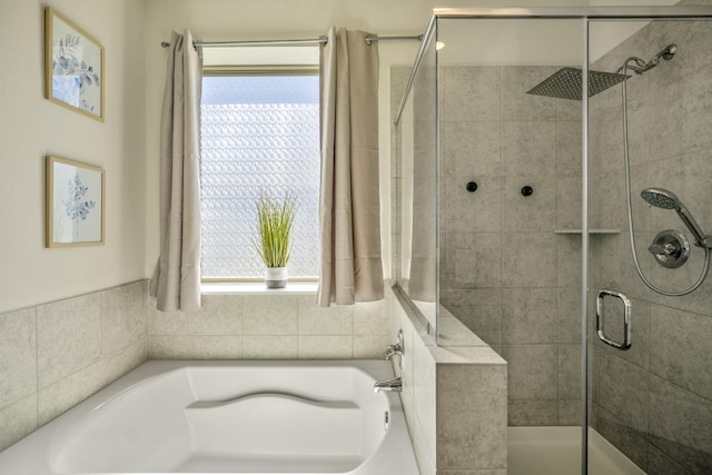 full bathroom with a wealth of natural light, a shower stall, and a garden tub