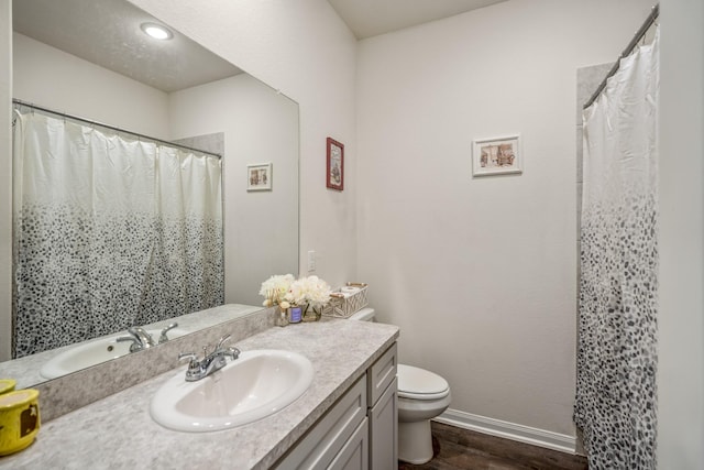 bathroom featuring baseboards, toilet, a shower with curtain, wood finished floors, and vanity