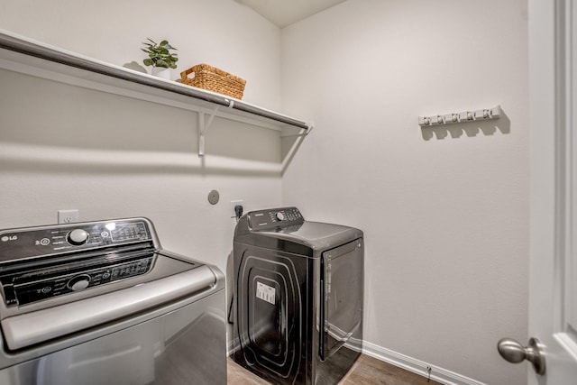 laundry room featuring laundry area, independent washer and dryer, baseboards, and wood finished floors