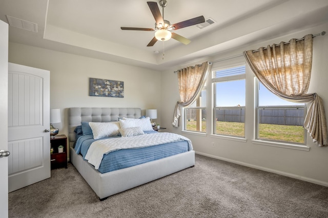 carpeted bedroom with visible vents, ceiling fan, a raised ceiling, and baseboards