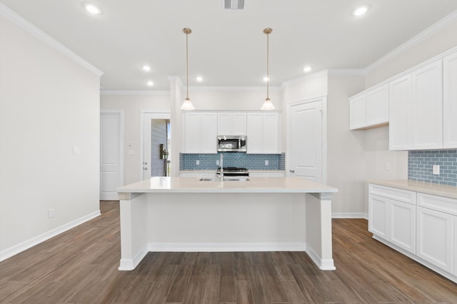 kitchen with dark wood-type flooring, white cabinets, stainless steel microwave, and a center island with sink