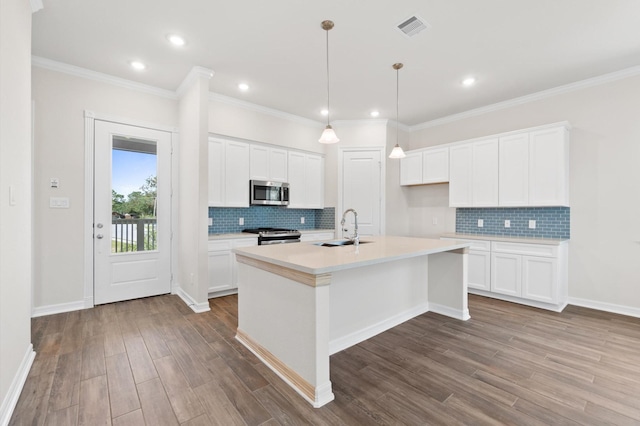 kitchen with visible vents, appliances with stainless steel finishes, a sink, an island with sink, and wood finished floors