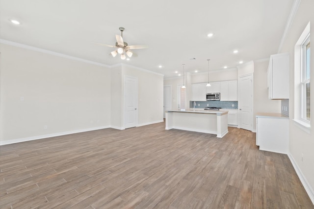 kitchen with tasteful backsplash, light wood-type flooring, open floor plan, and stainless steel microwave