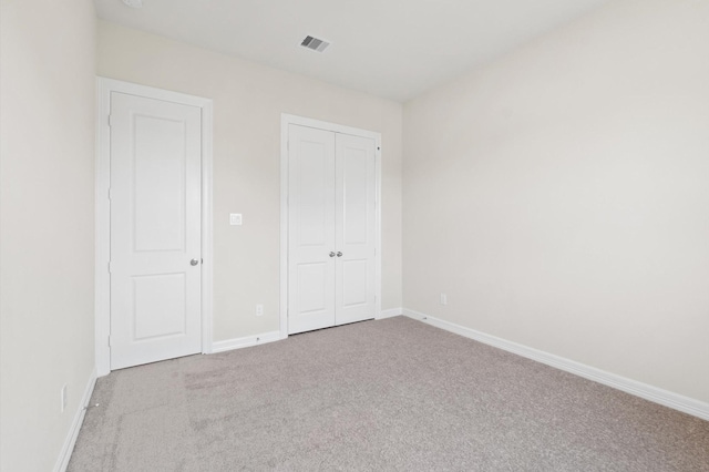 unfurnished bedroom with a closet, carpet flooring, visible vents, and baseboards