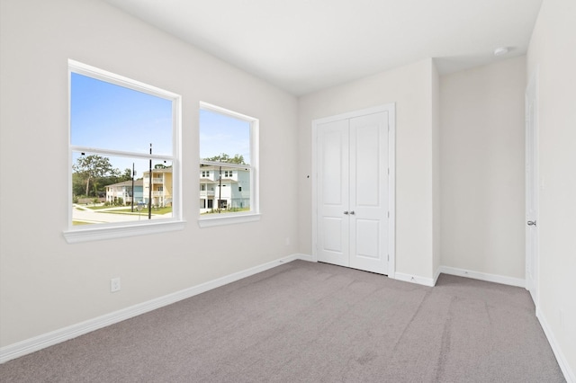 unfurnished bedroom with carpet, a closet, and baseboards