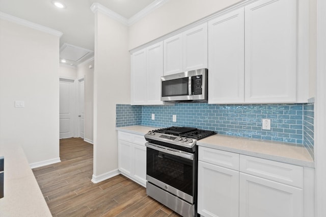 kitchen with light wood finished floors, stainless steel appliances, light countertops, decorative backsplash, and ornamental molding