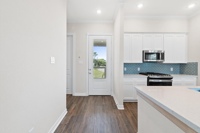 kitchen with dark wood finished floors, ornamental molding, stainless steel appliances, light countertops, and backsplash