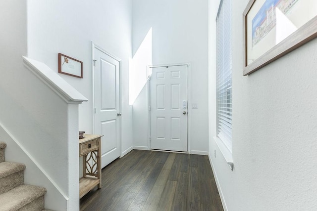 interior space featuring dark wood-type flooring, stairway, and baseboards