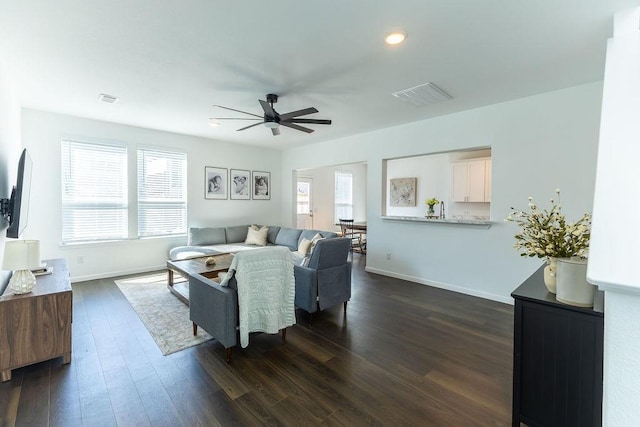 living area featuring ceiling fan, dark wood-style flooring, visible vents, and baseboards