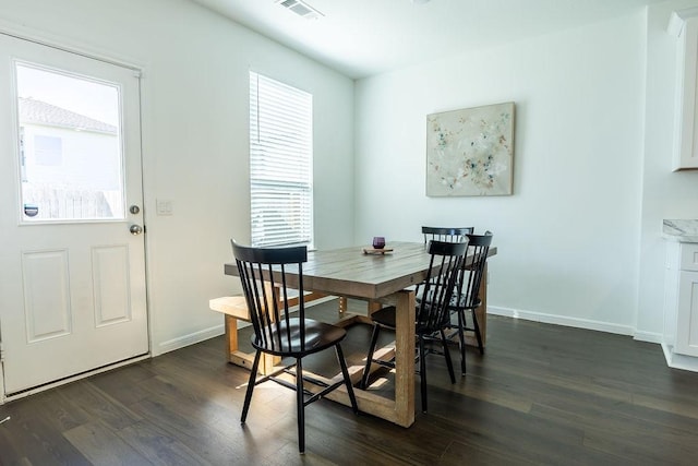 dining area with dark wood finished floors, visible vents, and baseboards