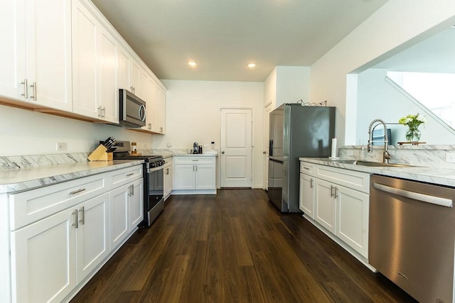 kitchen featuring dark wood-style flooring, stainless steel appliances, white cabinetry, a sink, and recessed lighting