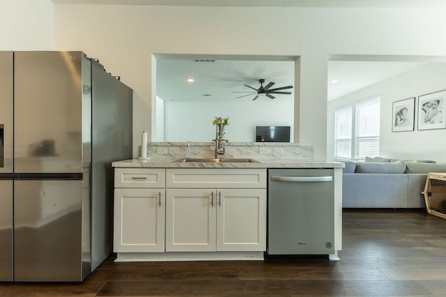 kitchen featuring light stone counters, stainless steel appliances, dark wood-type flooring, a sink, and white cabinetry