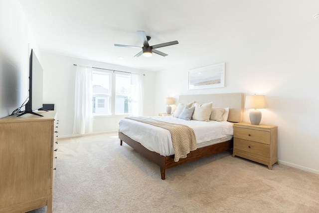 bedroom with light colored carpet, ceiling fan, and baseboards