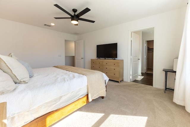 bedroom with ceiling fan, visible vents, baseboards, and light colored carpet