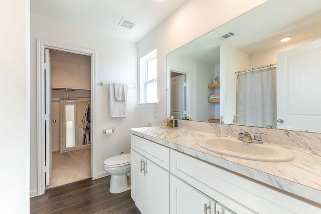 bathroom with toilet, visible vents, wood finished floors, and vanity