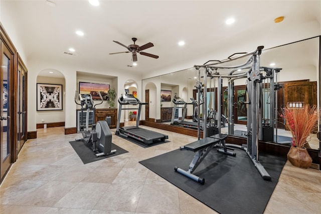 exercise area featuring a ceiling fan, visible vents, baseboards, recessed lighting, and arched walkways