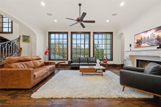 living area featuring visible vents, dark wood-type flooring, stairway, a lit fireplace, and recessed lighting