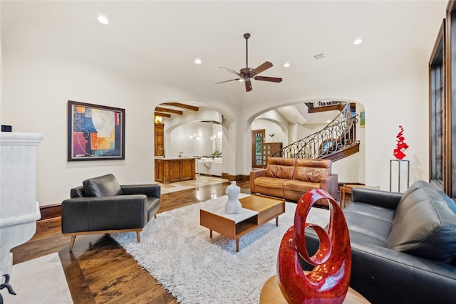 living area with stairway, wood finished floors, recessed lighting, arched walkways, and ceiling fan