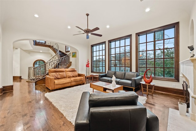 living room featuring stairway, recessed lighting, a fireplace, and arched walkways