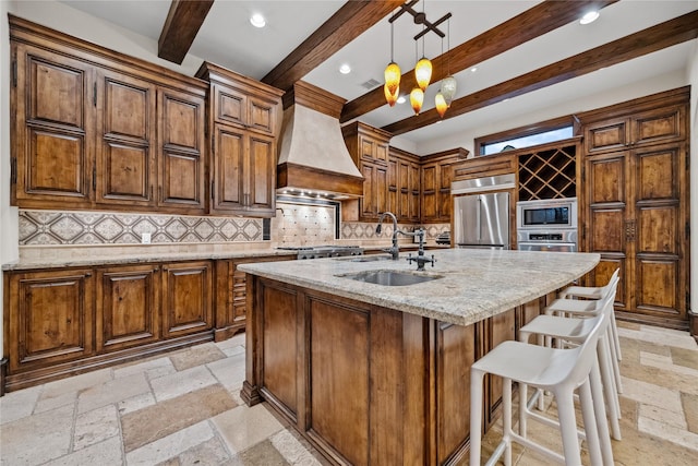 kitchen featuring custom exhaust hood, built in appliances, a sink, and stone tile flooring