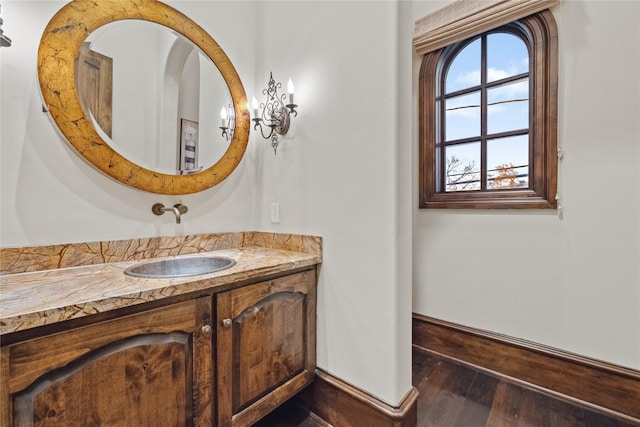 bathroom with baseboards, vanity, and hardwood / wood-style flooring